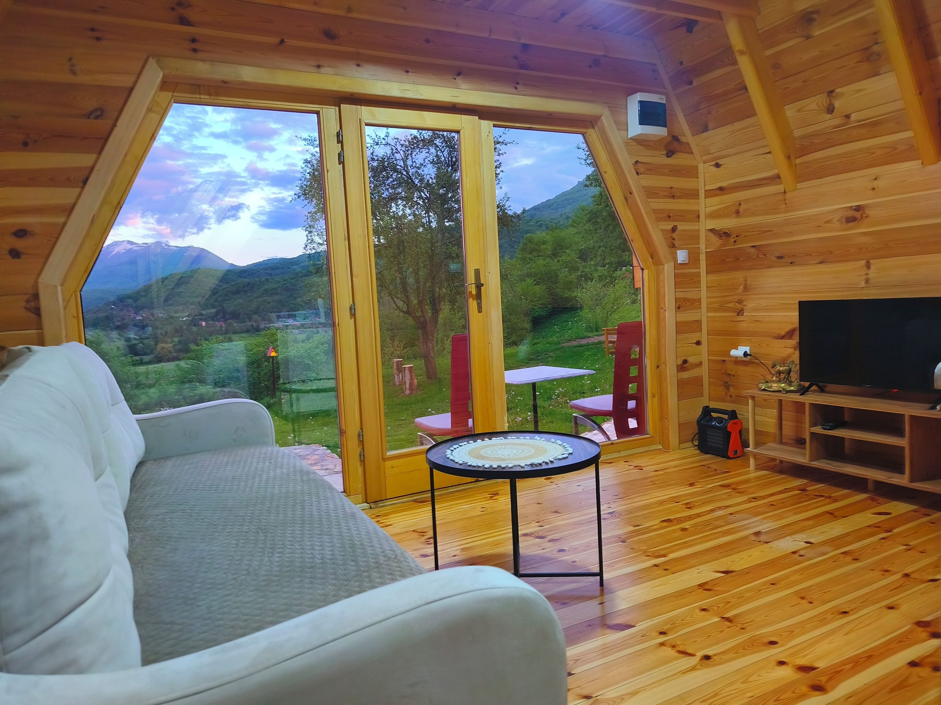 A wooden interior with a sofa, a television, and a table with a decorative item.