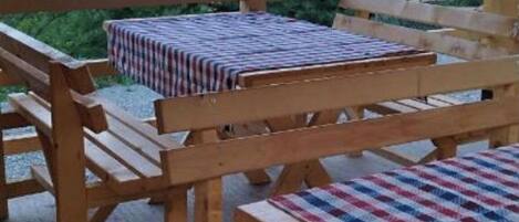 A wooden outdoor seating area with tables and benches, overlooking a mountainous landscape.