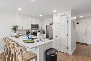 A modern kitchen with white cabinets, a central island, and a refrigerator. - New at Maravilla • Gulf View Balcony • Free Beach Service • Sleeps 8 (Miramar Beach)