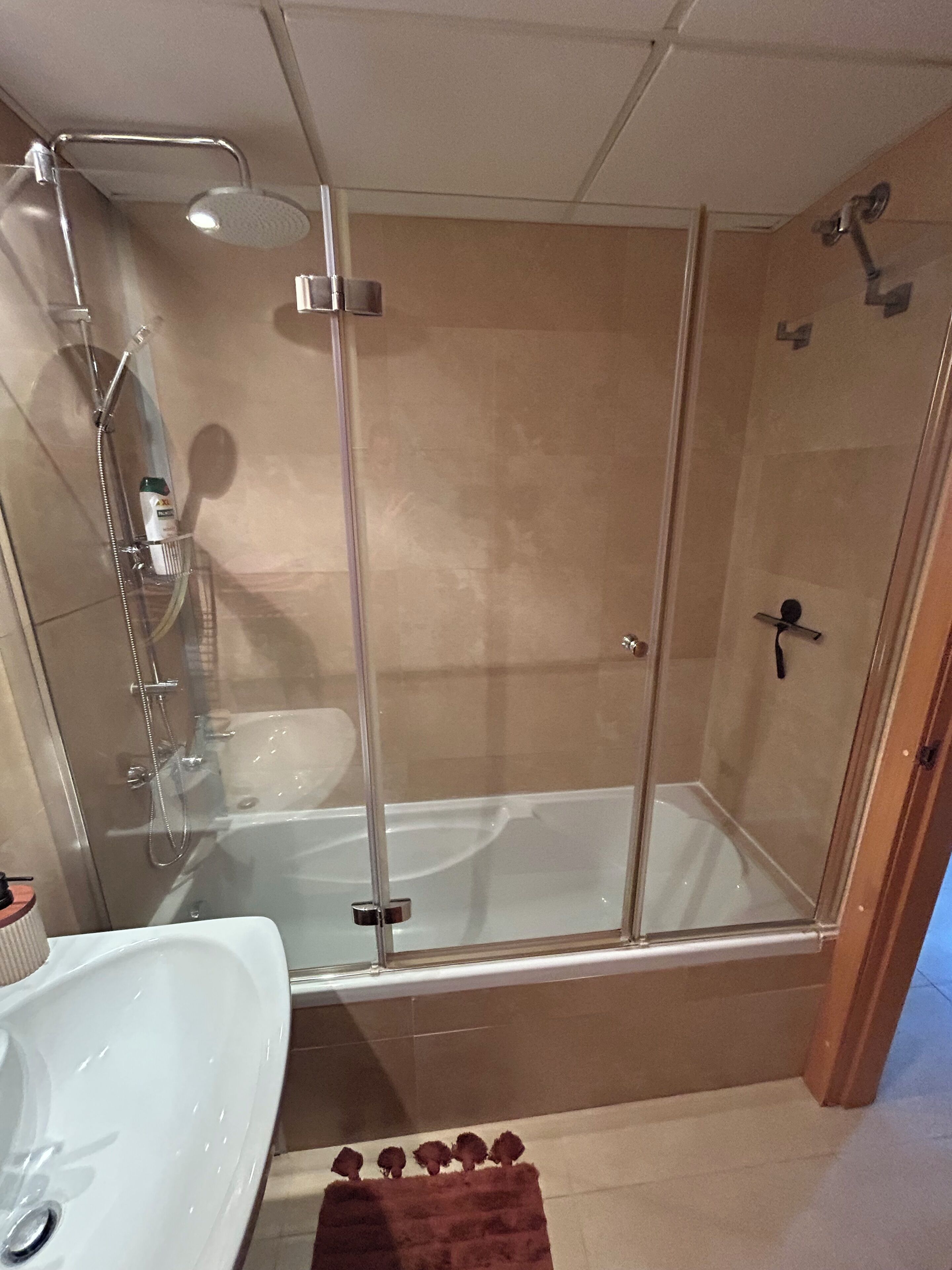 Un bagno con doccia vetro, lavandino bianco e vasca da bagno.