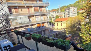 Un balcon avec une table, des chaises et des jardinières suspendues.