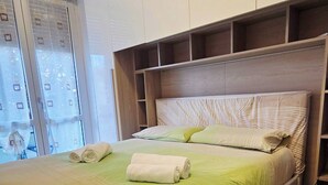 Une chambre moderne dotée d’un grand lit, de rangements intégrés et offrant une vue sur la ville.