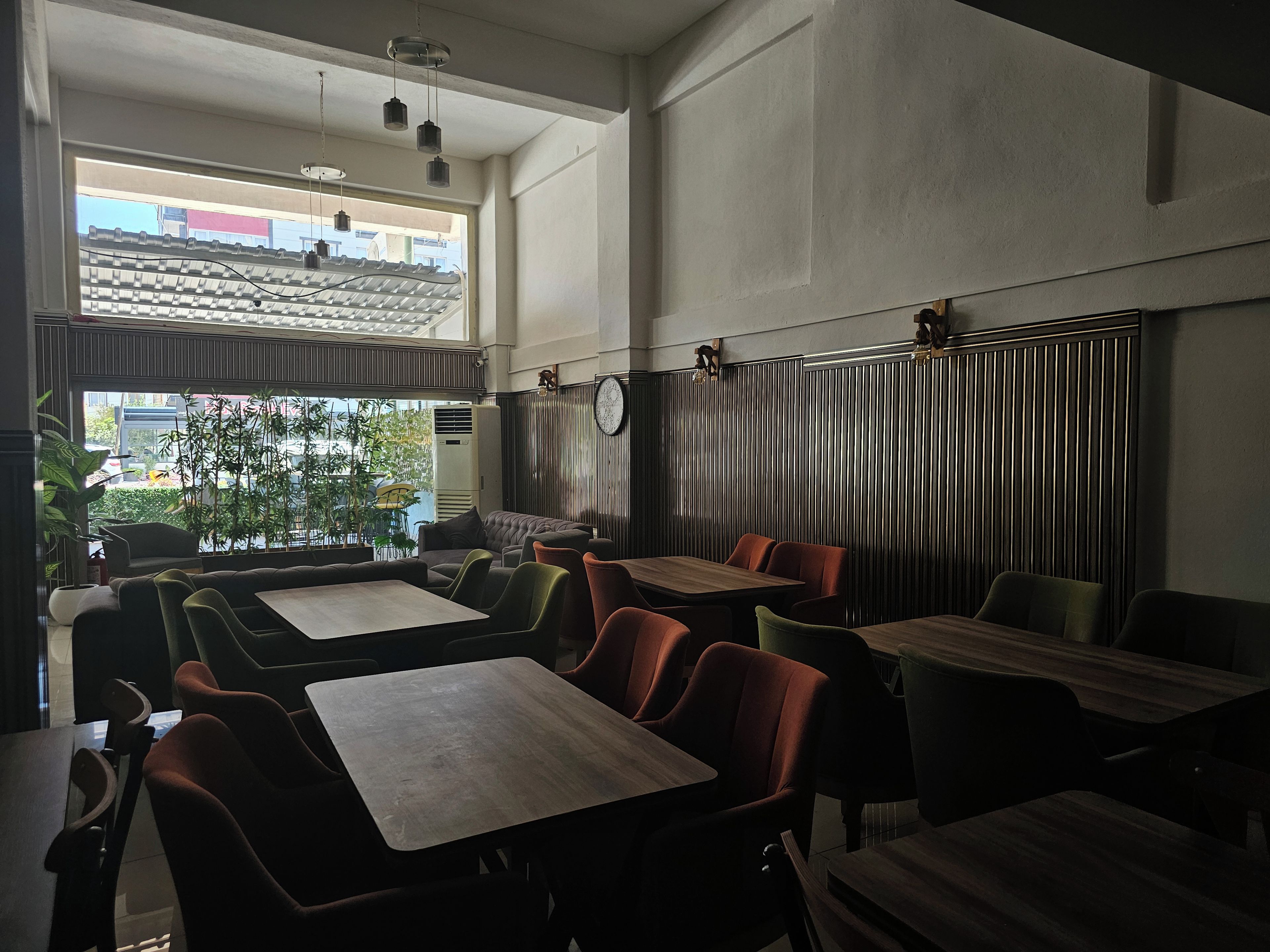 Interior de restaurante con techos altos, ventanas amplias y una variedad de opciones de asientos, incluyendo cabinas y mesas.