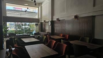 Interior de restaurante con techos altos, ventanas amplias y una variedad de opciones de asientos, incluyendo cabinas y mesas.