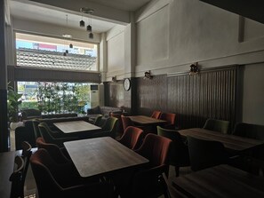 A restaurant interior with high ceilings, large windows, and a mix of seating arrangements including booths and tables. - Ayışık Otel (Kepez)