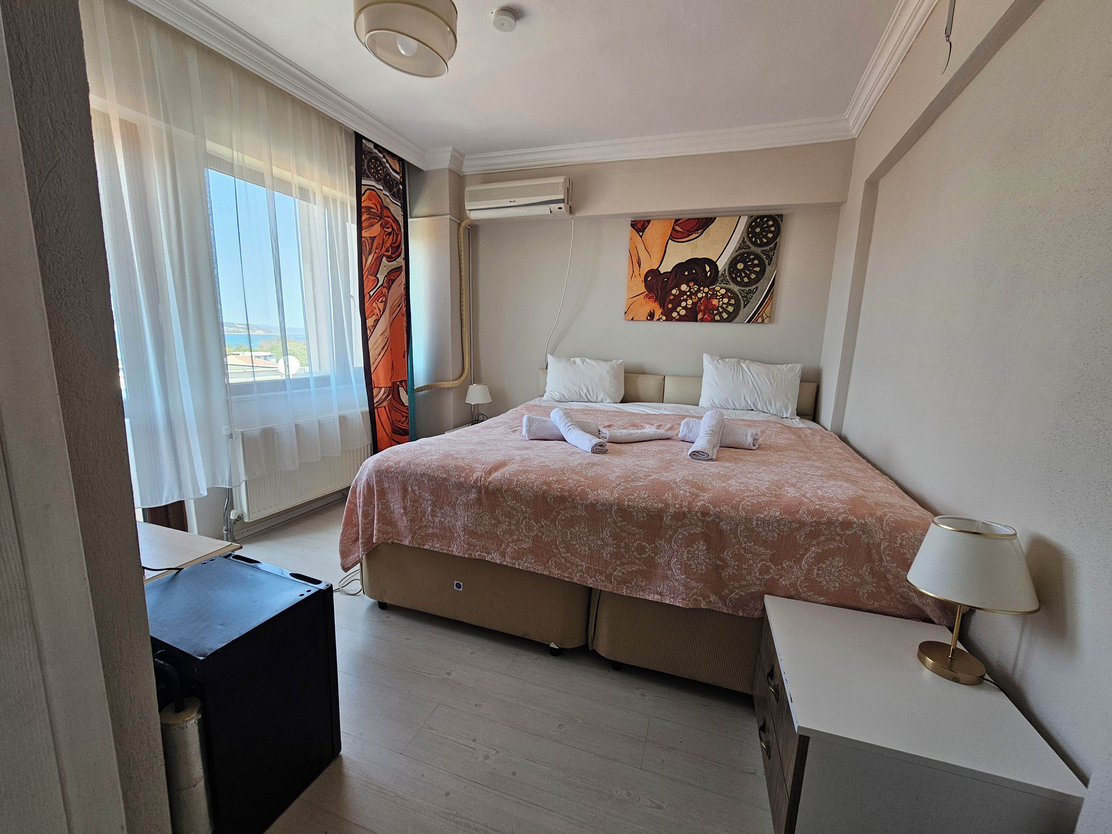 Ein Hotelzimmer mit Bett, Schreibtisch, Lampe und einem Bild an der Wand.