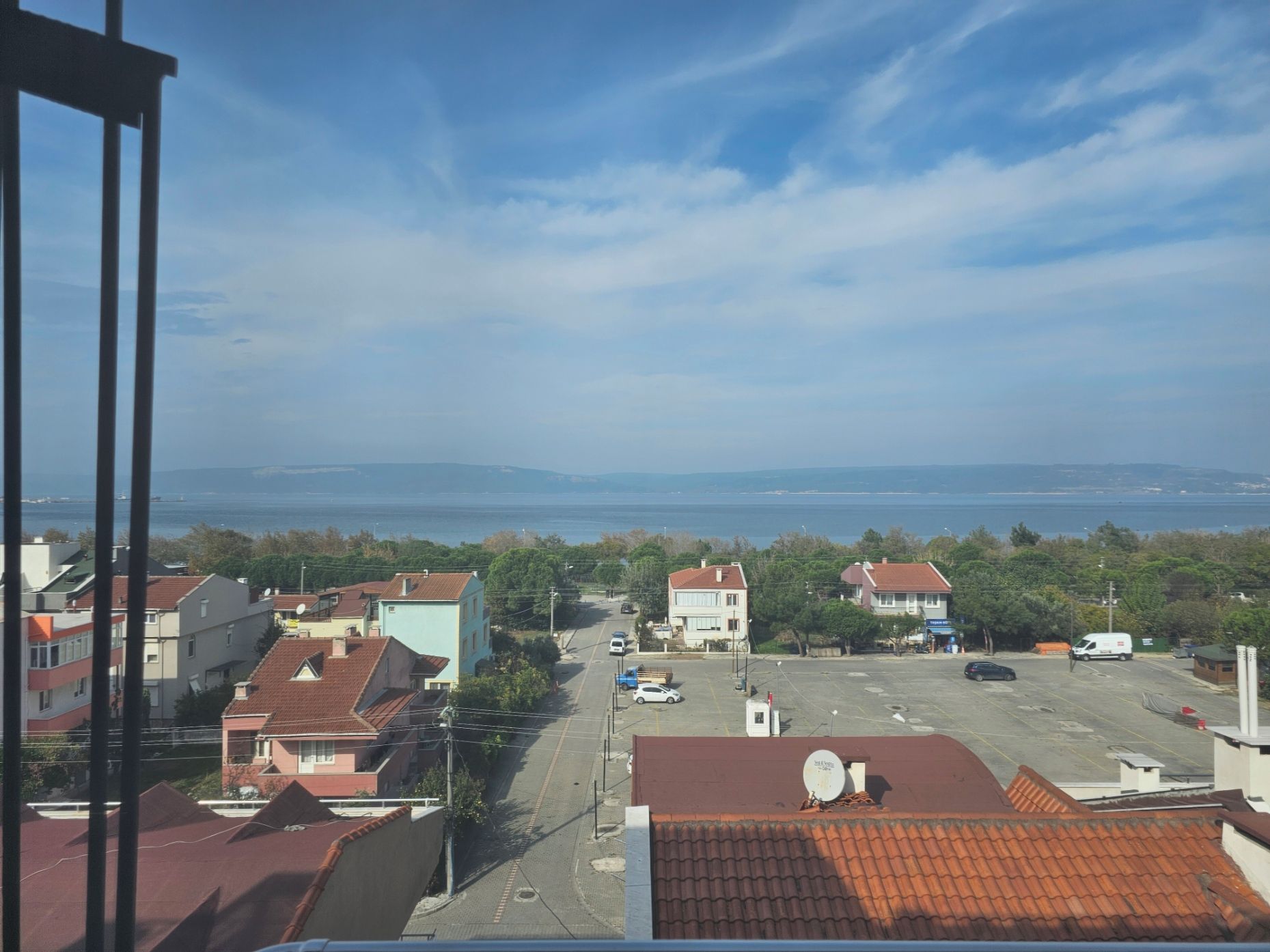 A residential area with houses, a parking lot, and a view of the sea.
