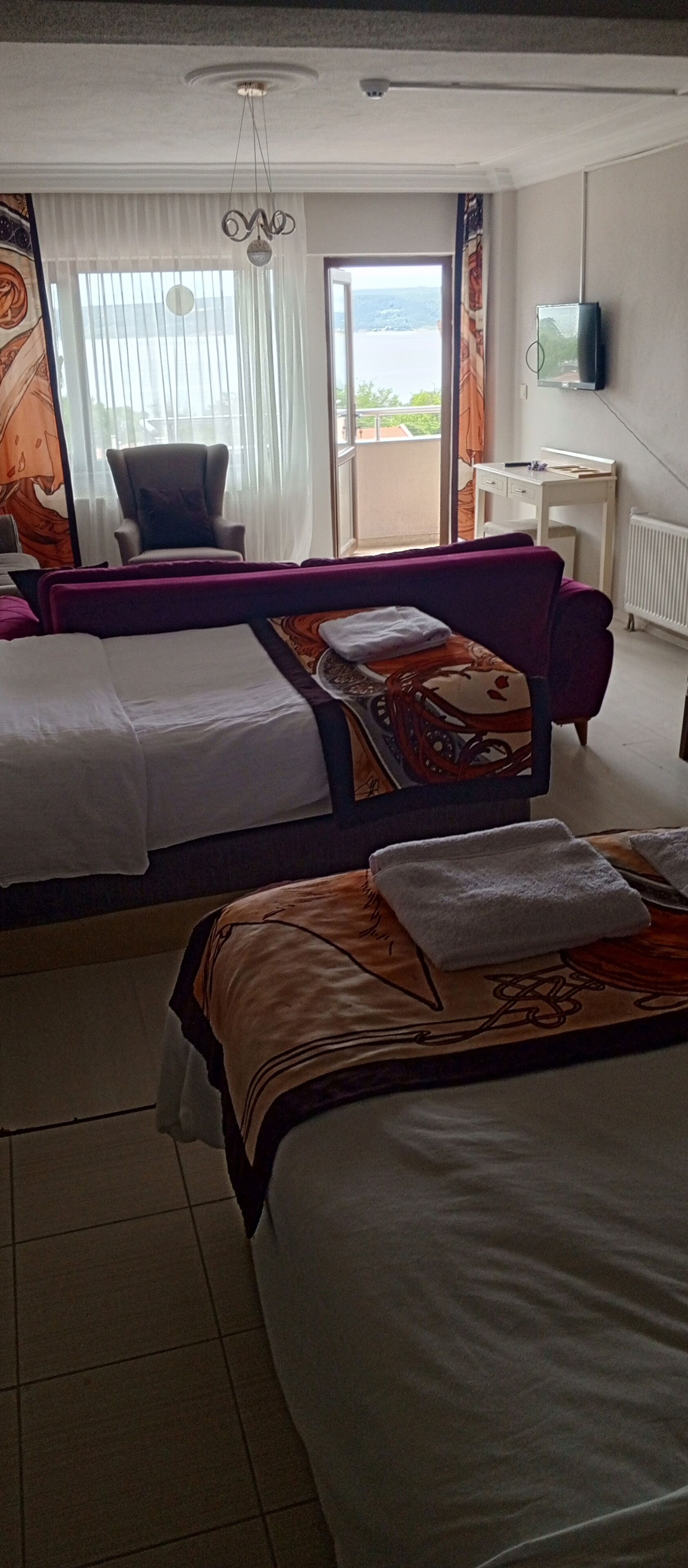Habitación de hotel con dos camas, una silla, un escritorio, un televisor y vistas al exterior.