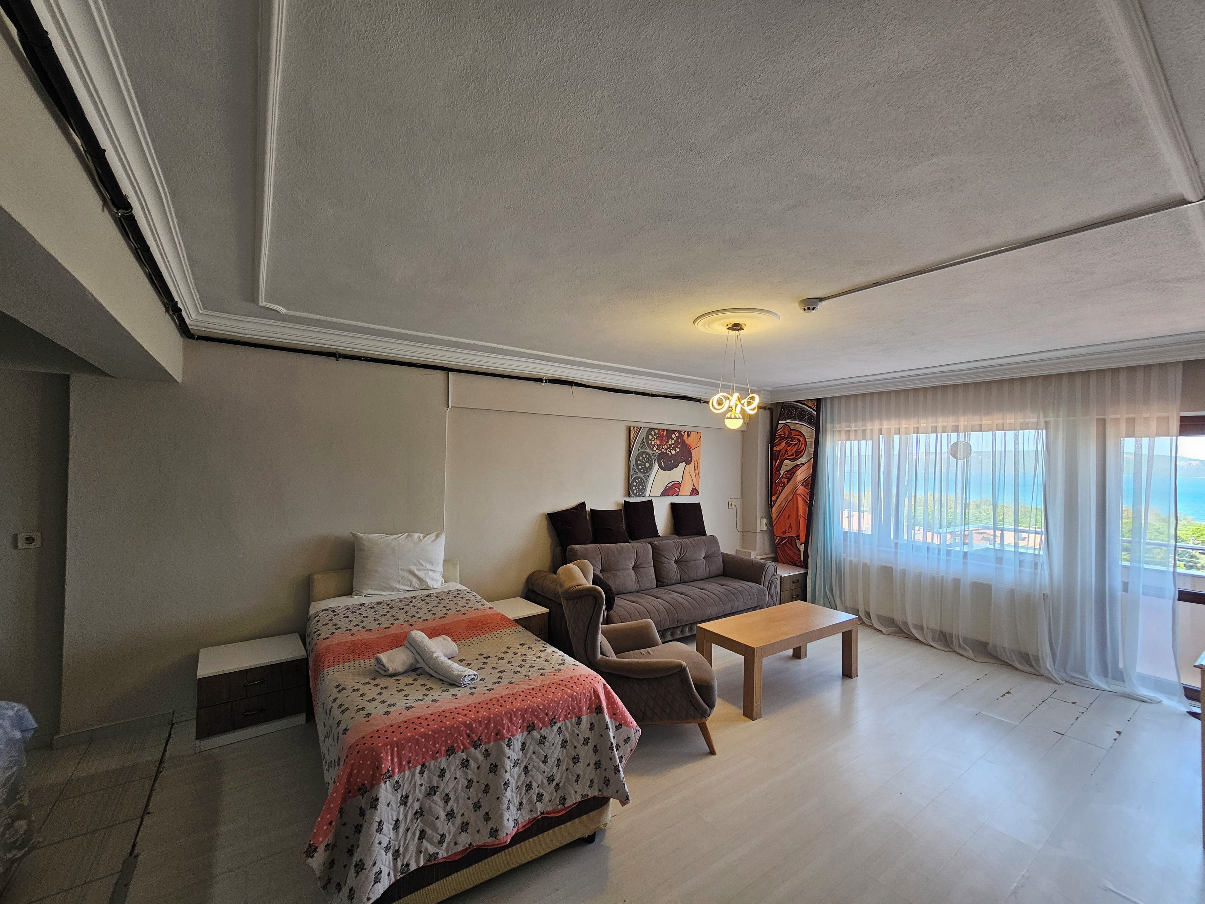 A hotel room with a bed, a sofa, a coffee table, and a large window with a view.