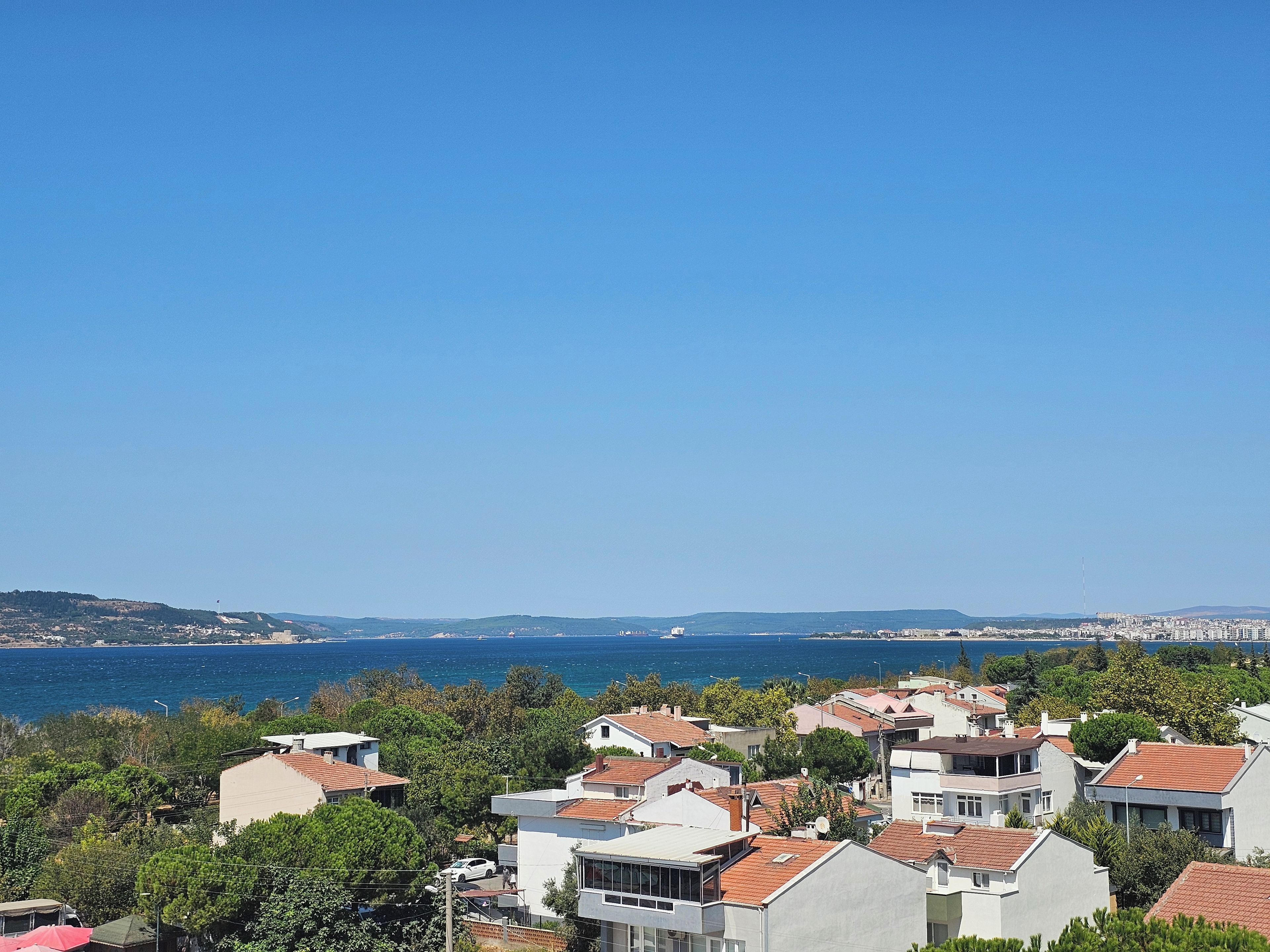 A coastal residential area with houses, a clear blue sky, and a view of the sea.