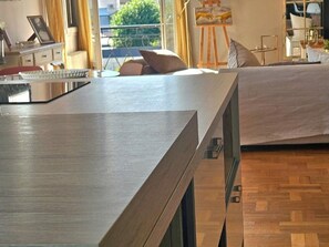 Un dormitorio moderno con un escritorio de madera, una cama con edredón blanco y vistas al exterior a través de una ventana.