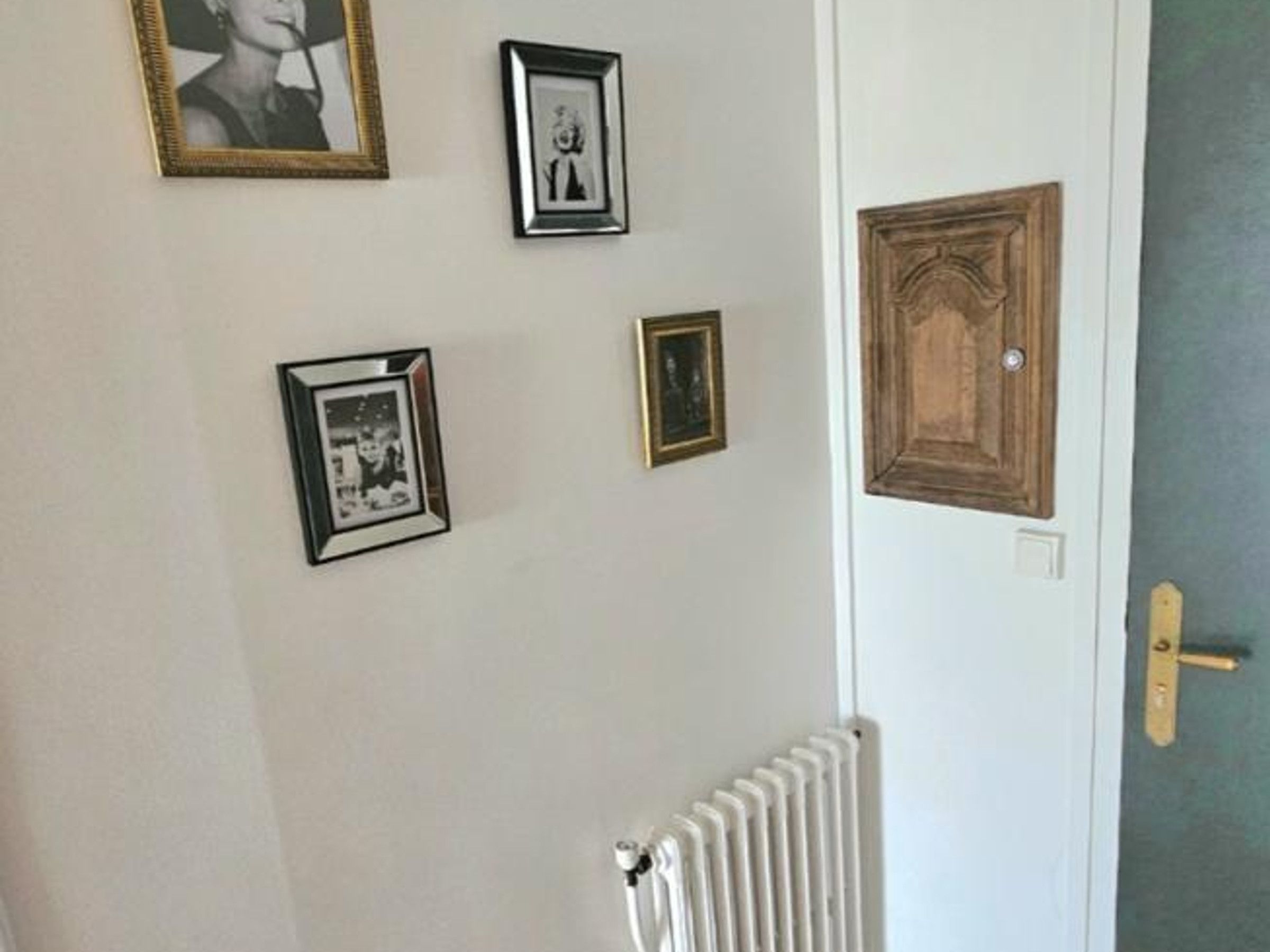 Una pared con varias fotografías enmarcadas y un radiador.