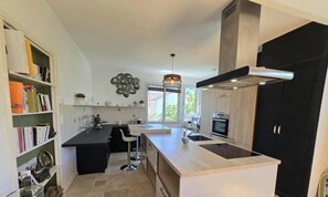 Una cocina moderna con una isla central, muebles negros y un ventanal grande.
