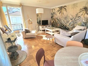 Una sala de estar con un sofá, una mesa de centro, un televisor y un mural en la pared.