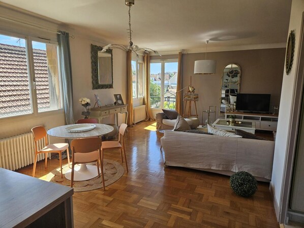 Ein gemütliches Zimmer mit Bett, Schreibtisch, Stuhl, Tisch und Fernseher.
