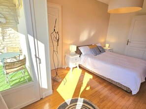 Un dormitorio con cama, mesitas de noche y ventana con vistas a un espacio exterior.