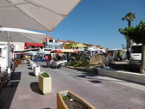 Ein belebter Markt mit verschiedenen Ständen und einem weißen Lieferwagen in der Nähe.
