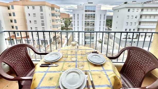 A balcony with a table set for two, overlooking a cityscape. - 2-bedroom apartment with parking, pool, and close to the beach in Roses (Roses)