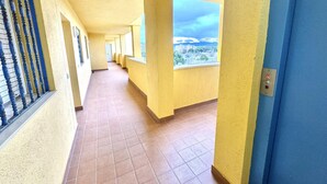 A corridor with yellow walls, blue doors, and windows with a view of buildings. - 2-bedroom apartment with parking, pool, and close to the beach in Roses (Roses)