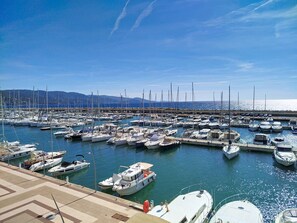 A marina with numerous boats docked, a clear sky, and a distant mountain range. - Studio with AC, sea view - 4 guests (Bormes-les-Mimosas)