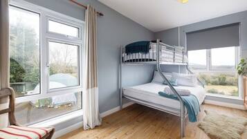 Une chambre avec un lit superposé, de grandes fenêtres, une chaise et un tapis.