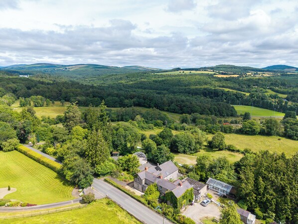 A rural landscape with a house surrounded by fields and trees.