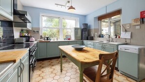 A kitchen with a wooden table, cabinets, a stove, and a dishwasher. - Large 9-Bed Wicklow Retreat • Sleeps 18+ • Valley Views • Sauna • Parking (Rathdrum)