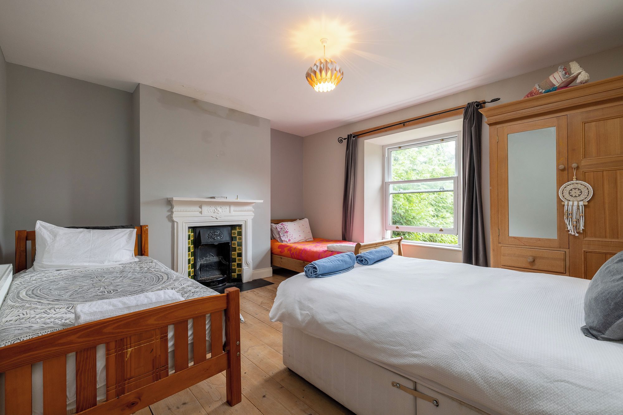 Een slaapkamer met twee bedden, een open haard, een raam met uitzicht en een kledingkast.