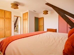 A bedroom with a bed, wooden wardrobe, and a staircase.