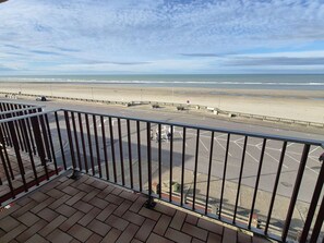 A view from a balcony overlooking a beach with a road and parking area. - Apartment with sea view - 4 guests (Cucq-Stella Plage)