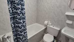 Ein Badezimmer mit Badewanne, Toilette und Waschbecken, alles in Weiß.