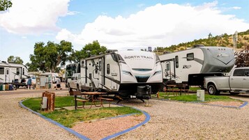 A North Trail Ultra Lite RV parked in a campground with other RVs, a picnic table, and a gravel path.