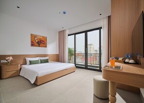A hotel room with a bed, bedside table, a desk with a chair, a large window, and a painting on the wall. - Solla Hotel (Ninh Binh)