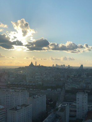 A cityscape with high-rise buildings, a prominent tower, and a clear sky with clouds. - Comfortable apartment on the 31st floor of a high-rise building! (Paris)