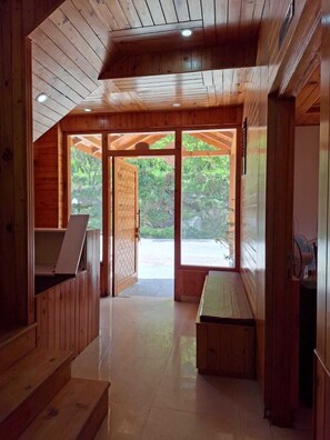 Interior de madera con un banco, una mesa y vistas a través de un ventanal.