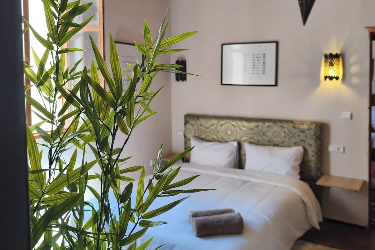 Un dormitorio con cama, luz empotrada en la pared y lámpara colgante.