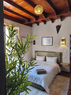 Un dormitorio con cama, luz empotrada en la pared y lámpara colgante.