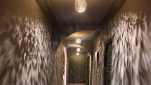 Un pasillo con paredes ornamentadas, piso estampado y lámparas esféricas colgantes.