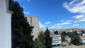 Un balcón con vista a un paisaje urbano, que incluye edificios y árboles.