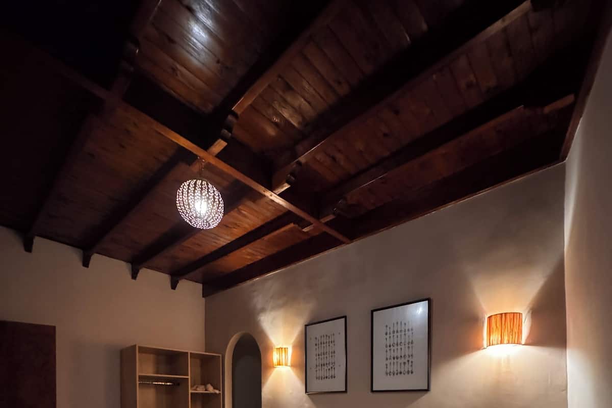 Un dormitorio con una cama grande, vigas de madera en el techo, un armario y apliques de pared.