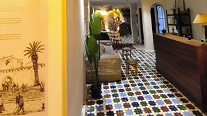 Vestíbulo de hotel con suelo de baldosas, un mostrador de recepción y un techo decorativo.