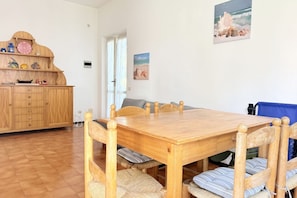 Ein Essbereich mit Holztisch und -stühlen, einem Holzkasten mit Dekoration und einem Bild an der Wand.