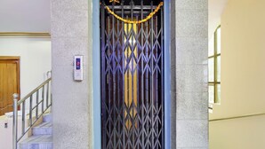 A metal gate with a security keypad, a staircase with a metal railing, and a door with a wooden frame.