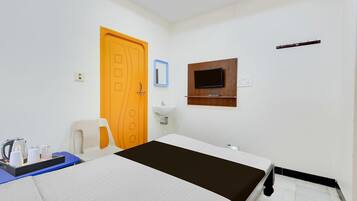 Een hotelkamer met een bed, een aan de muur bevestigde televisie, een wastafel en een deur.