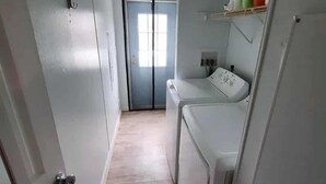 A laundry room with a washing machine, a dryer, and a door leading to another room. - Easy Access Ramp Entry  3-bedroom 2 bathroom Harrison Cottage with AC (Harrison)