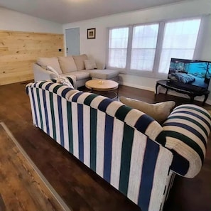 A living room with a striped sofa, a round coffee table, and a television.