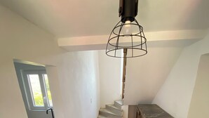 Una escalera que lleva a un segundo piso, una pequeña mesa de madera y una ventana con vistas a la vegetación.