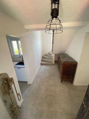 Eine Treppe führt zu einer zweiten Etage, ein kleiner Holztisch und ein Fenster mit Blick auf Grünflächen.