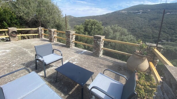 Un patio al aire libre con barandillas de piedra, una mesa y sillas.