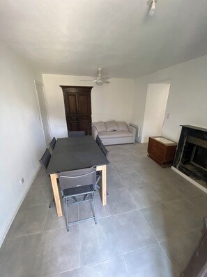 A spacious room with a dining table, chairs, a sofa, a fireplace, and a ceiling fan. - Quiet village house 10 minutes from the sea (Poggio)